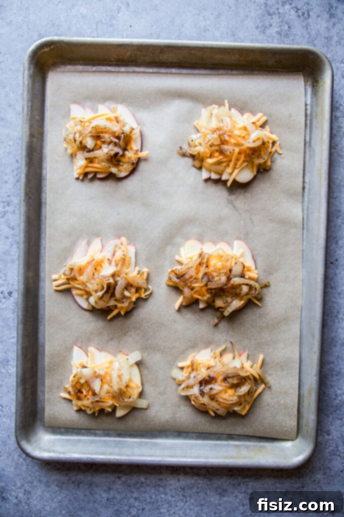 Sliced apples, shredded cheddar, and caramelized rum onions arranged on a baking sheet before adding pastry