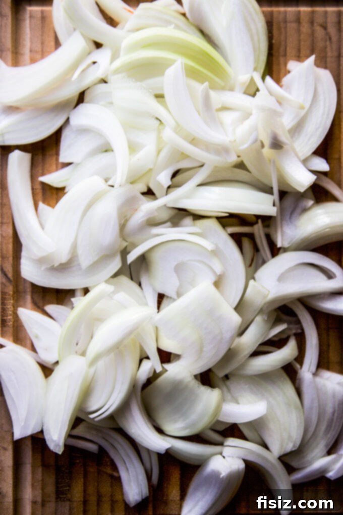 Ultimate French Onion Baked Potatoes 4 Sliced raw yellow onions on a cutting board, ready for caramelization.