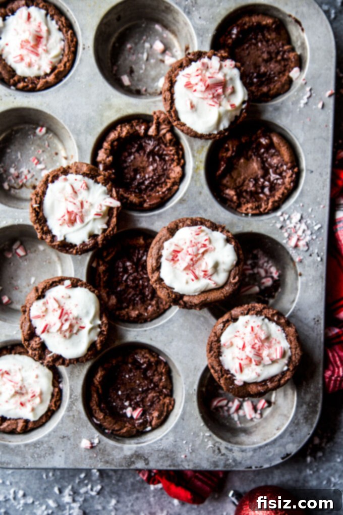 Frosty Peppermint Cream Chocolate Cookie Cups 8 A vertical stack of three chocolate cookie cups with whipped peppermint cream and candy cane garnish