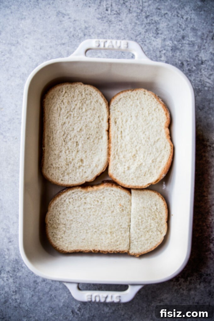 Savory Italian Brunch Bake 4 Slices of white bread neatly arranged in the bottom of a 9x13 baking dish, forming the base for the casserole