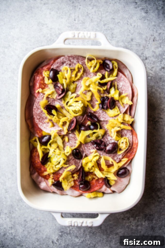 Savory Italian Brunch Bake 5 Layers of deli meats, pepperoncini, and olives arranged over a bread base in a baking dish