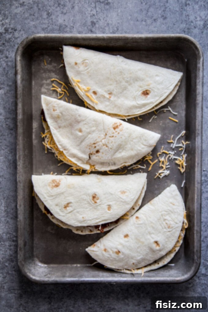 Smoky Brisket Tacos with a Crunchy Shell 6 crispy bbq beef tacos folded over on a baking sheet