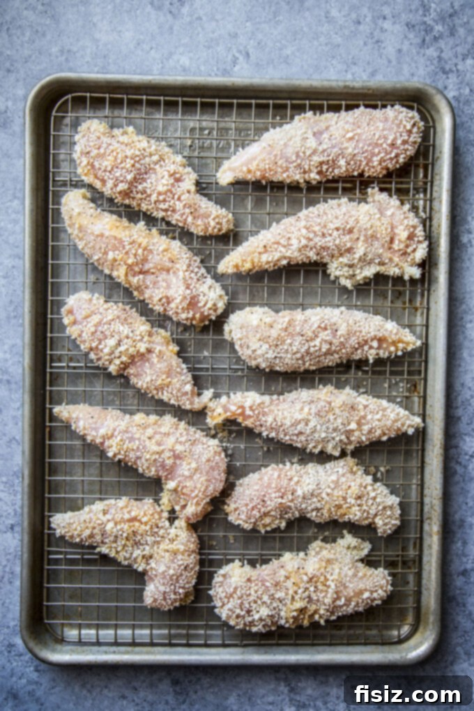 Honey Harissa Glazed Chicken Tenders 8 Coated chicken tenders arranged on a wire rack, ready for baking in the oven.