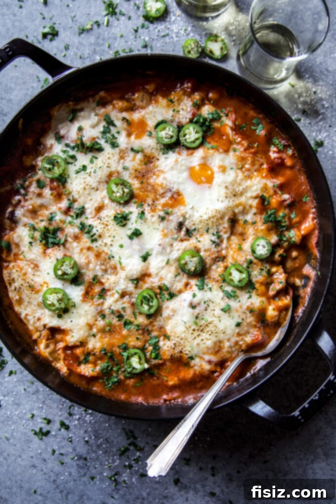 One-Pan Chorizo and White Bean Enchilada Bake 6 The finished chorizo and white bean enchilada skillet with perfectly baked eggs and melted cheese, garnished with parsley.