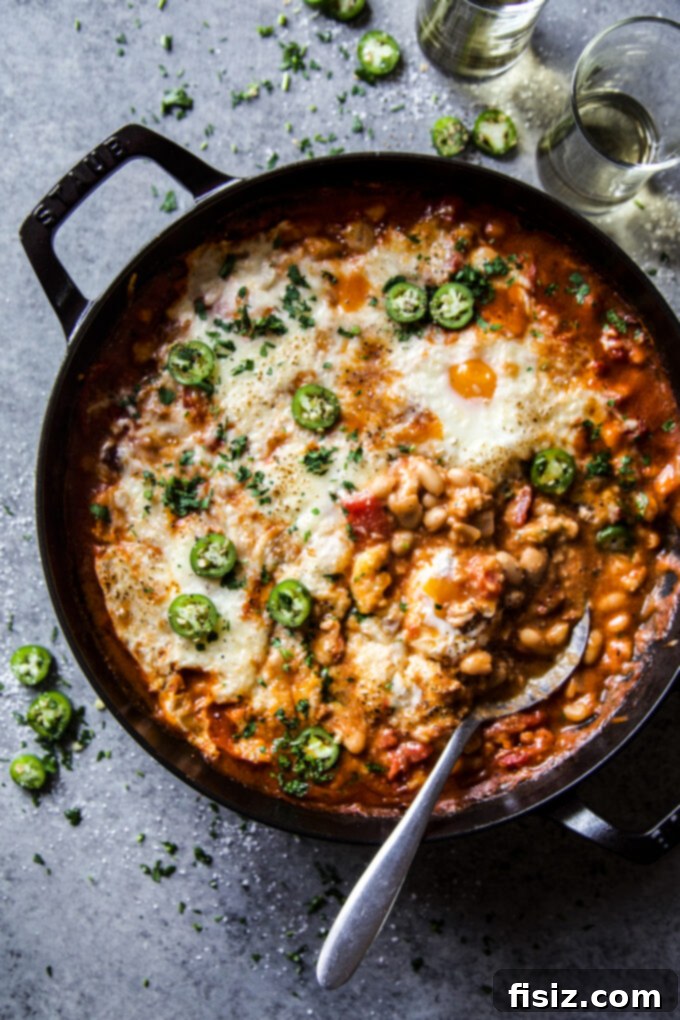 One-Pan Chorizo and White Bean Enchilada Bake 7 A generous serving of Chorizo & White Bean Enchilada Skillet, showing the rich sauce, beans, chorizo, and melted cheese with egg.