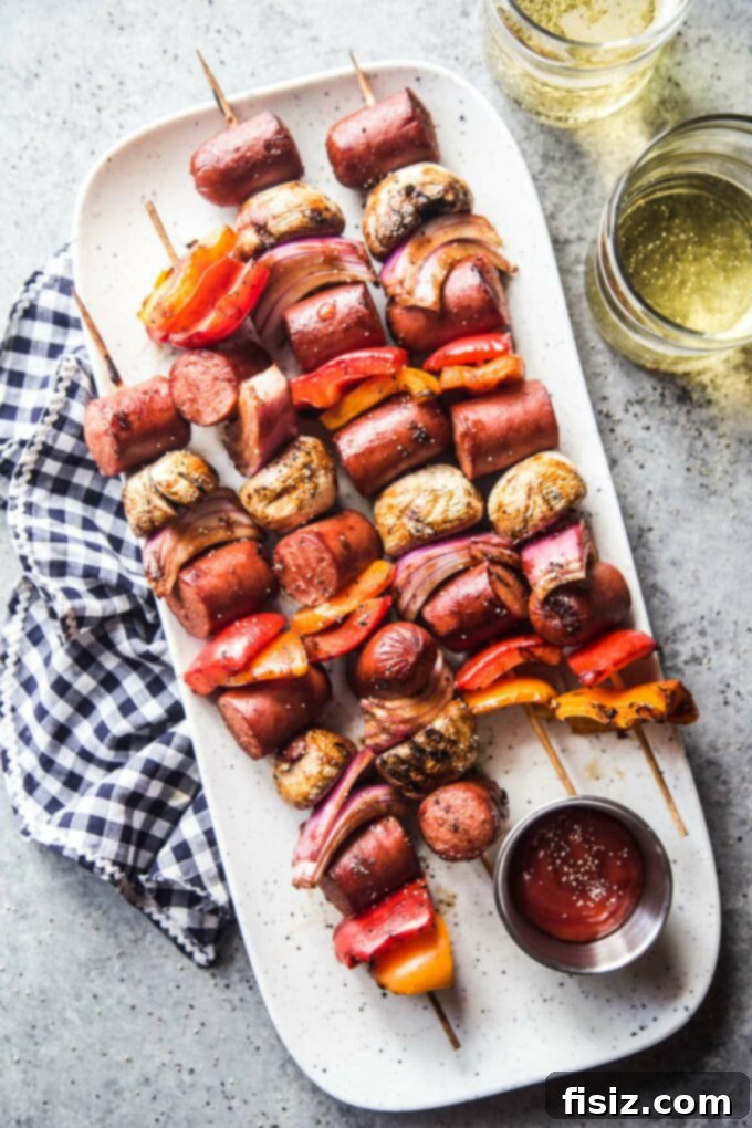 Epic Hot Dog Skewers 2 Delicious Loaded Hot Dog Skewers grilling on a barbecue with vibrant vegetables