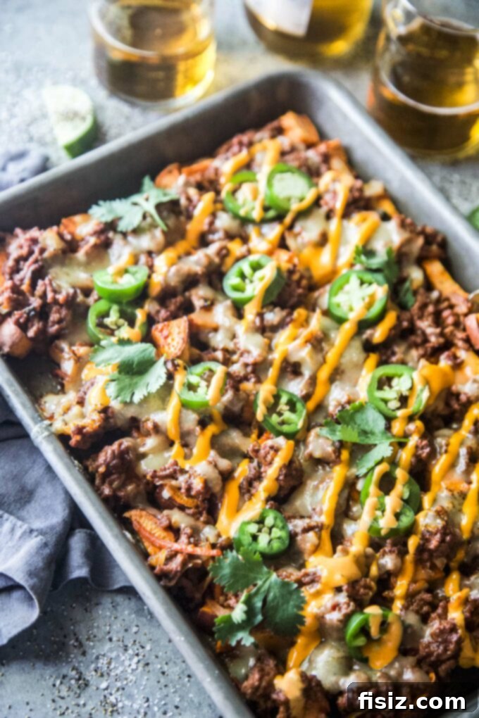 Korean BBQ Nachos Supreme 3 Close-up of crispy sweet potato slices topped with richly seasoned ground beef, melted white cheddar, and a sprinkle of fresh scallions.