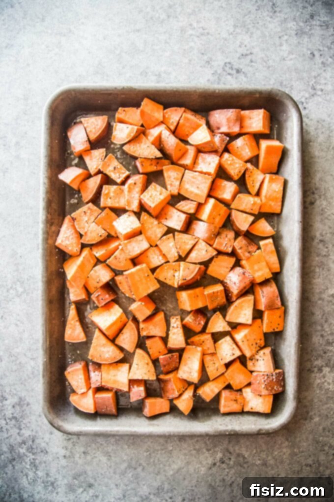 Korean BBQ Nachos Supreme 5 Cubed sweet potatoes, seasoned and spread on a baking sheet, ready for roasting.