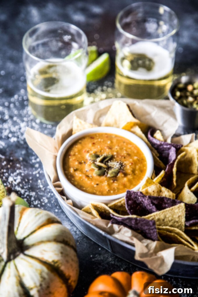 Tangy Heat Pumpkin Tomatillo Salsa 8 A selection of tortilla chips and fresh vegetables arranged around a bowl of Spiced Pumpkin Tomatillo Salsa.