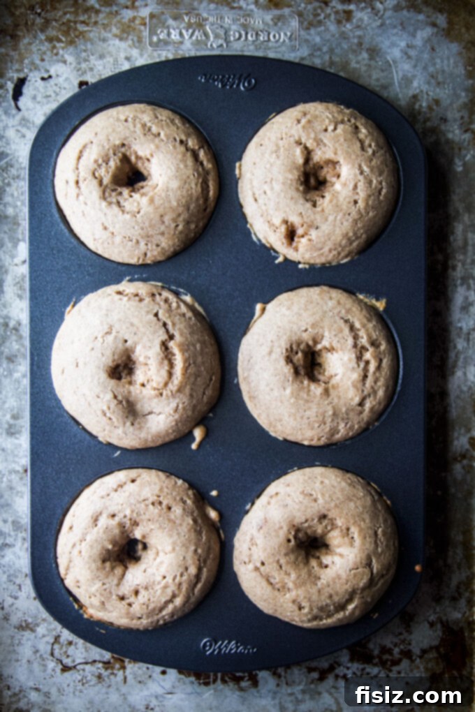 Heavenly Baked Coconut Cardamom Pecan Doughnuts 6 Baked doughnuts cooling on a wire rack after baking