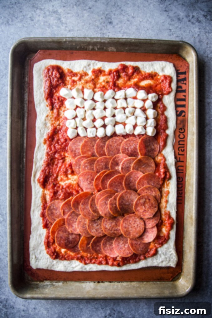 Uncooked stocking shaped pizza with mozzarella balls and pepperoni arranged