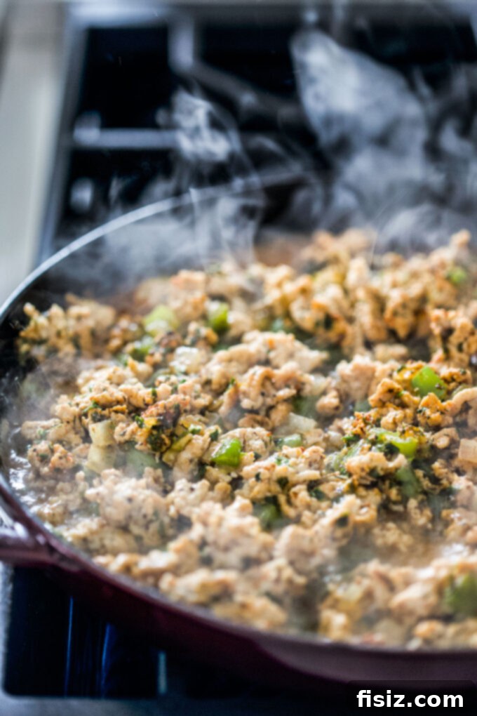 One-Pan Buffalo Chicken Chili Pasta 5 Ground chicken cooking in a large skillet with diced onions and green bell peppers.