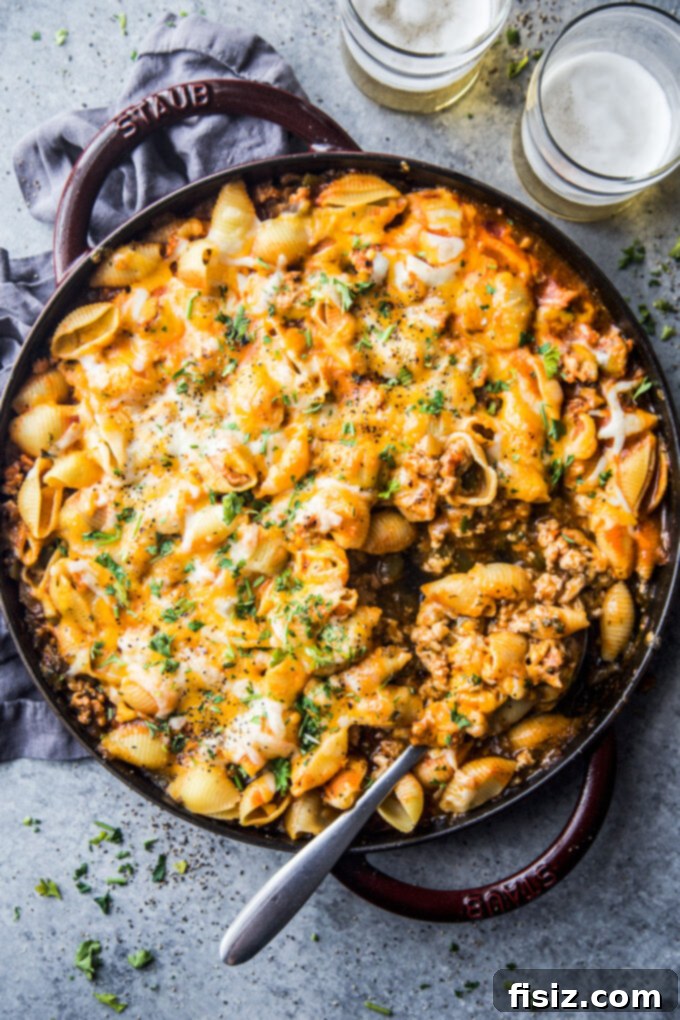One-Pan Buffalo Chicken Chili Pasta 7 A large serving spoon scooping Buffalo Chicken Chili Pasta Skillet from the pan, showing the rich texture.