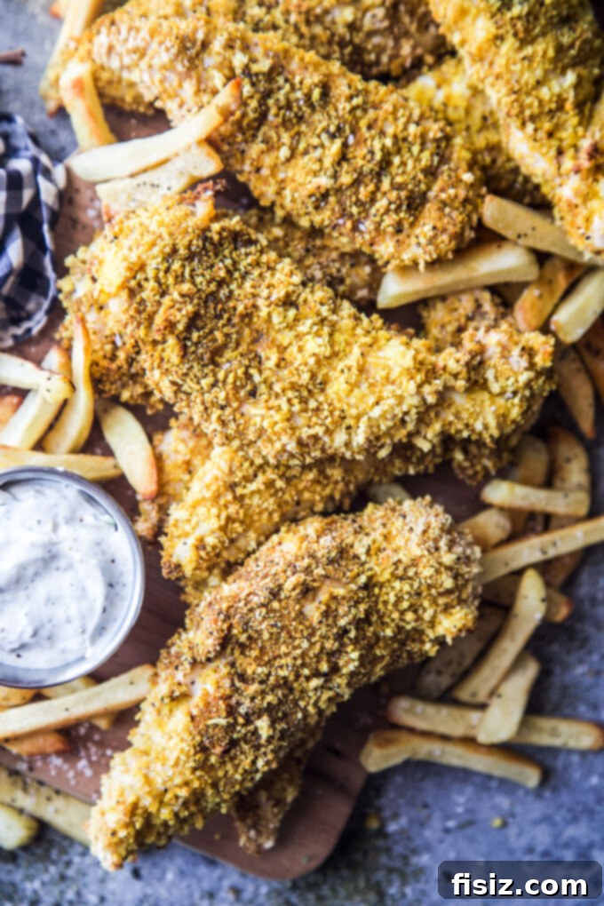Zesty Indian Chicken Tenders with a Cooling Ranch Dip 3 Close-up of baked Indian Spiced Chicken Tenders on a baking sheet, golden and crispy.