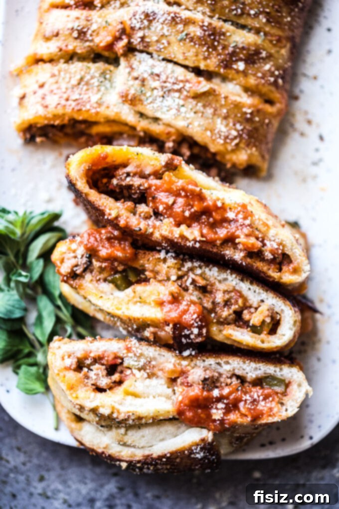Savory American Lamb Stromboli 10 A beautifully arranged spread featuring a whole American Lamb Stromboli, sliced, with a side of sauce