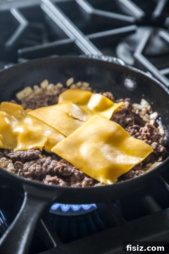 Deli-Style Chopped Cheese Deviled Eggs 5 Ground beef in a skillet, generously covered with melting cheddar cheese slices, ready to be chopped in