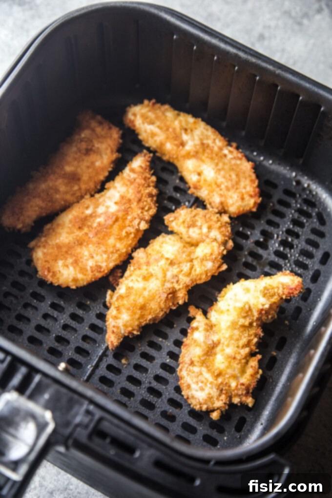 Golden-brown chicharron chicken tenders cooking in the air fryer basket