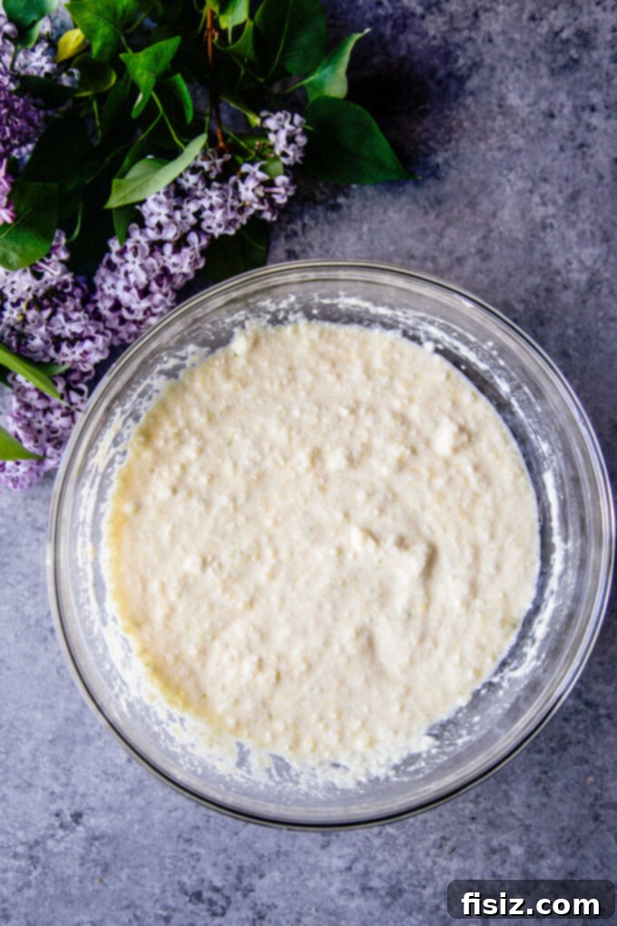 A bowl of wet ingredients for Coconut Lime Ricotta Muffins, including ricotta and lime zest.
