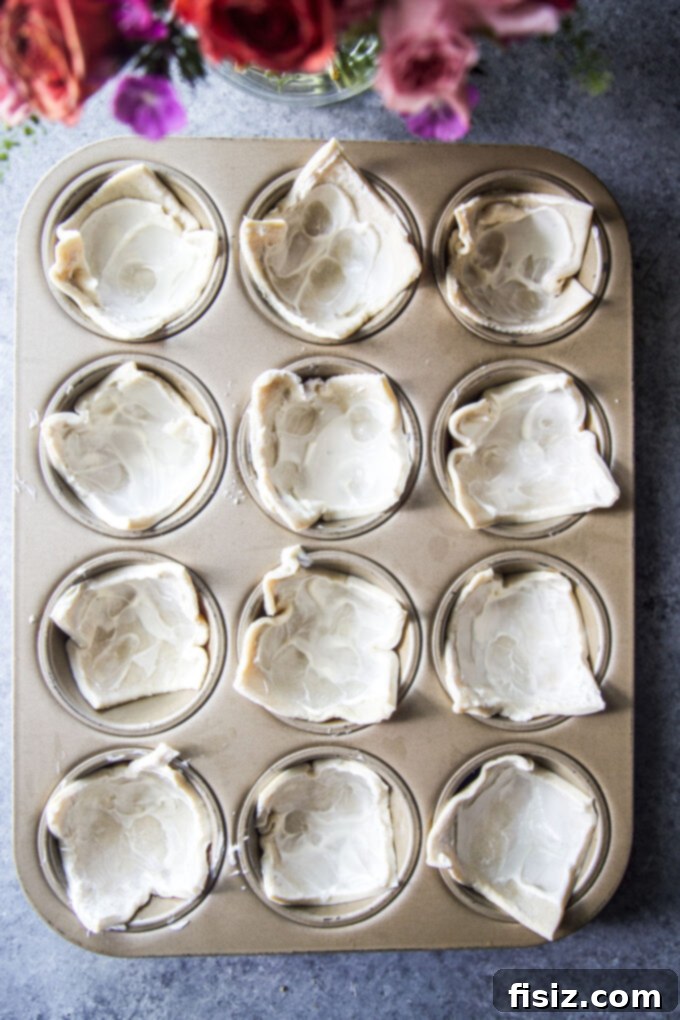 Savory Tomato Tarts 6 Puff pastry squares gently pressed into muffin cups, forming the base of the tarts.
