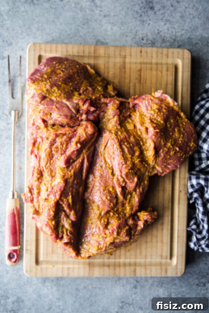 Tikka Masala Spiced American Butterflied Lamb 6 Butterflied leg of lamb generously coated with Tikka Masala marinade on a cutting board, ready for chilling.