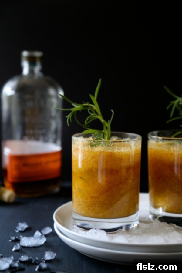 Foodie Fridays Peach Rosemary Bourbon Sparkler 5 An elegantly presented Peach-Rosemary Bourbon Sparkler cocktail, showcasing its amber hue, effervescent bubbles, and attractive garnishes of peach and rosemary.