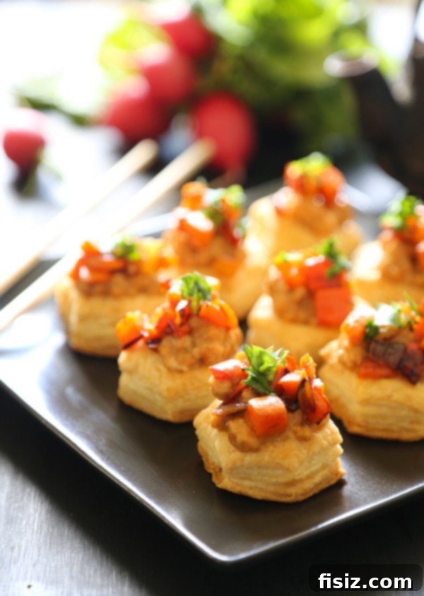 Golden brown spicy Asian chicken puff pastry bites with a side of hoisin peanut sauce, garnished with fresh herbs.